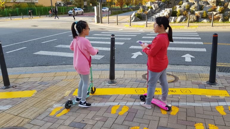 등굣길 횡단보도 앞 노란발자국 위에 서 있는 아이들