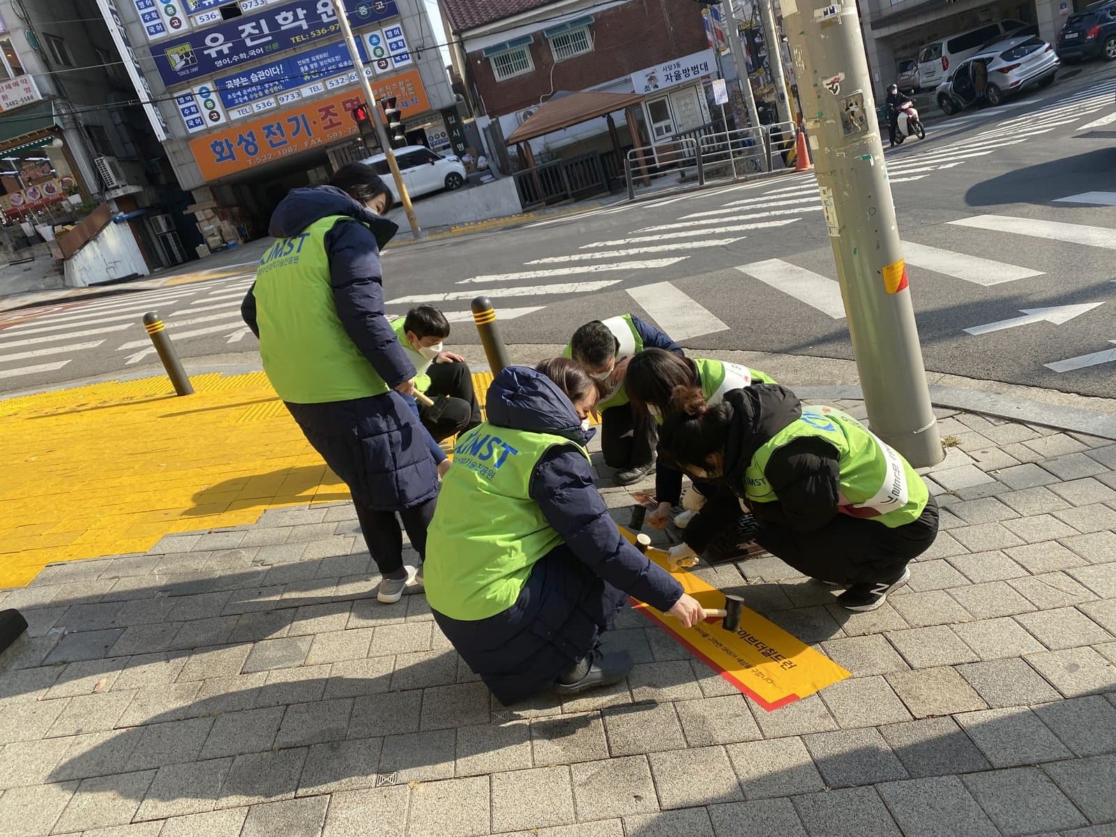 자원봉사자와 함께 횡단 대기공간에 노란발자국을 붙이는 장면