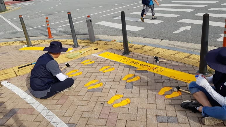 보도 바닥에 노란발자국 그래픽을 부착 시공하는 현장