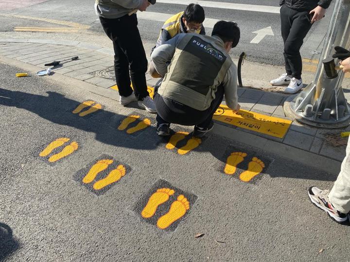 횡단보도 앞 인도에 노란발자국을 붙이는 현장 팀