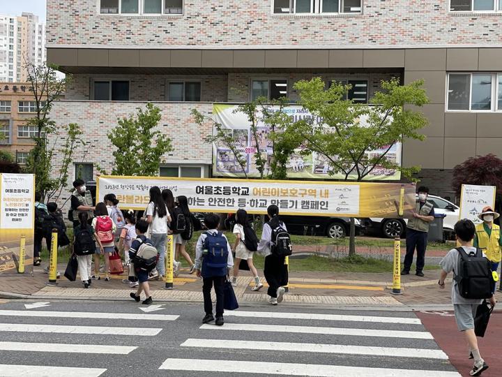 노란볼라드가 선 학교 앞 횡단보도를 건너는 아이들